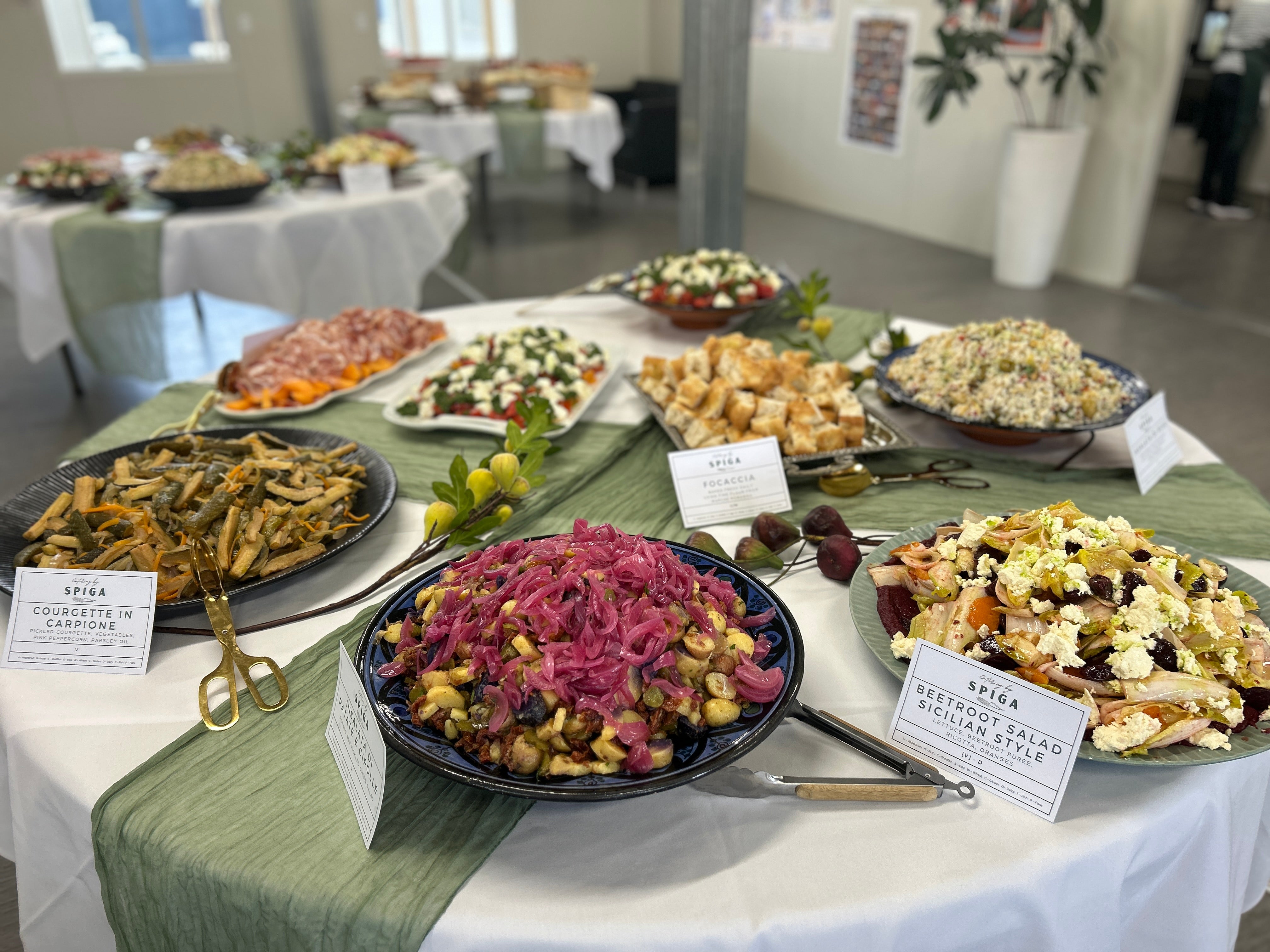 Table with various food dishes labeled for different cuisines in a room setting.