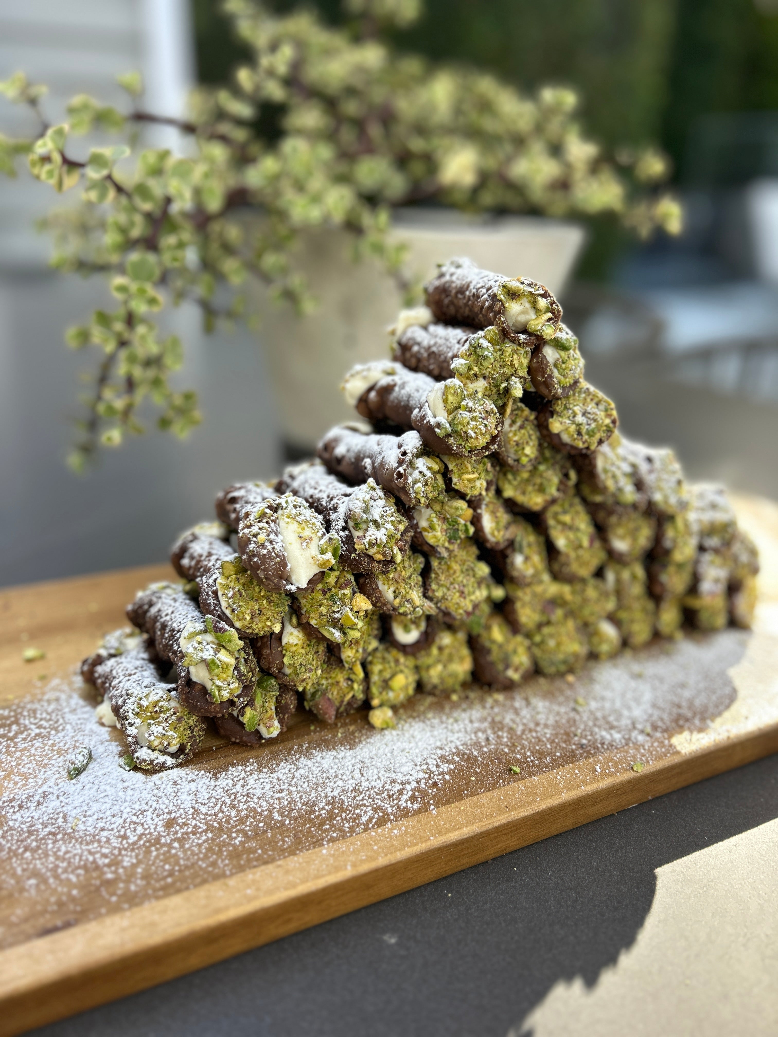 Decorative pastry stack on a wooden board with a blurred outdoor background