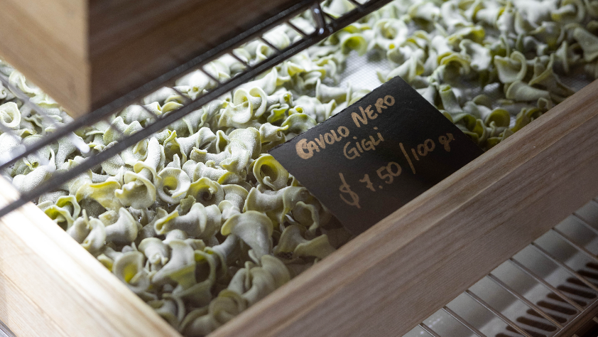 Dried pasta with a price tag labeled 'Ovolo Nero Gigio' on a tiled surface.